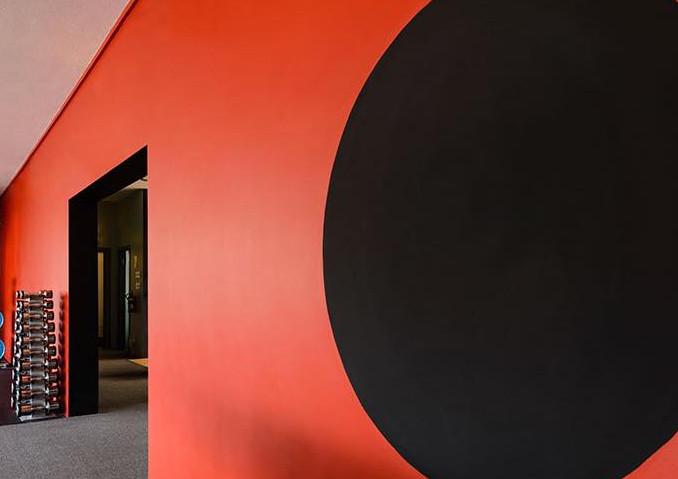 Vibrant red wall with a large black circle, hinting at modern commercial painting services.