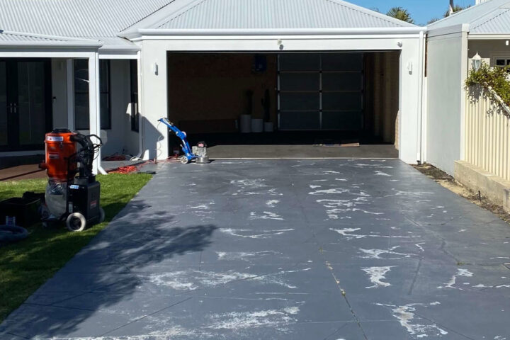 Driveway resurfacing in Austin's Ferry: worn concrete driveway with cleaning equipment.