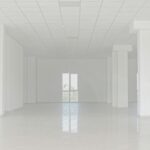 Empty white commercial space with tiled floor and columns