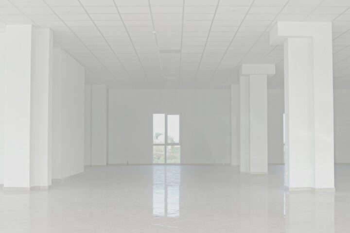 Empty white commercial space with tiled floor and columns