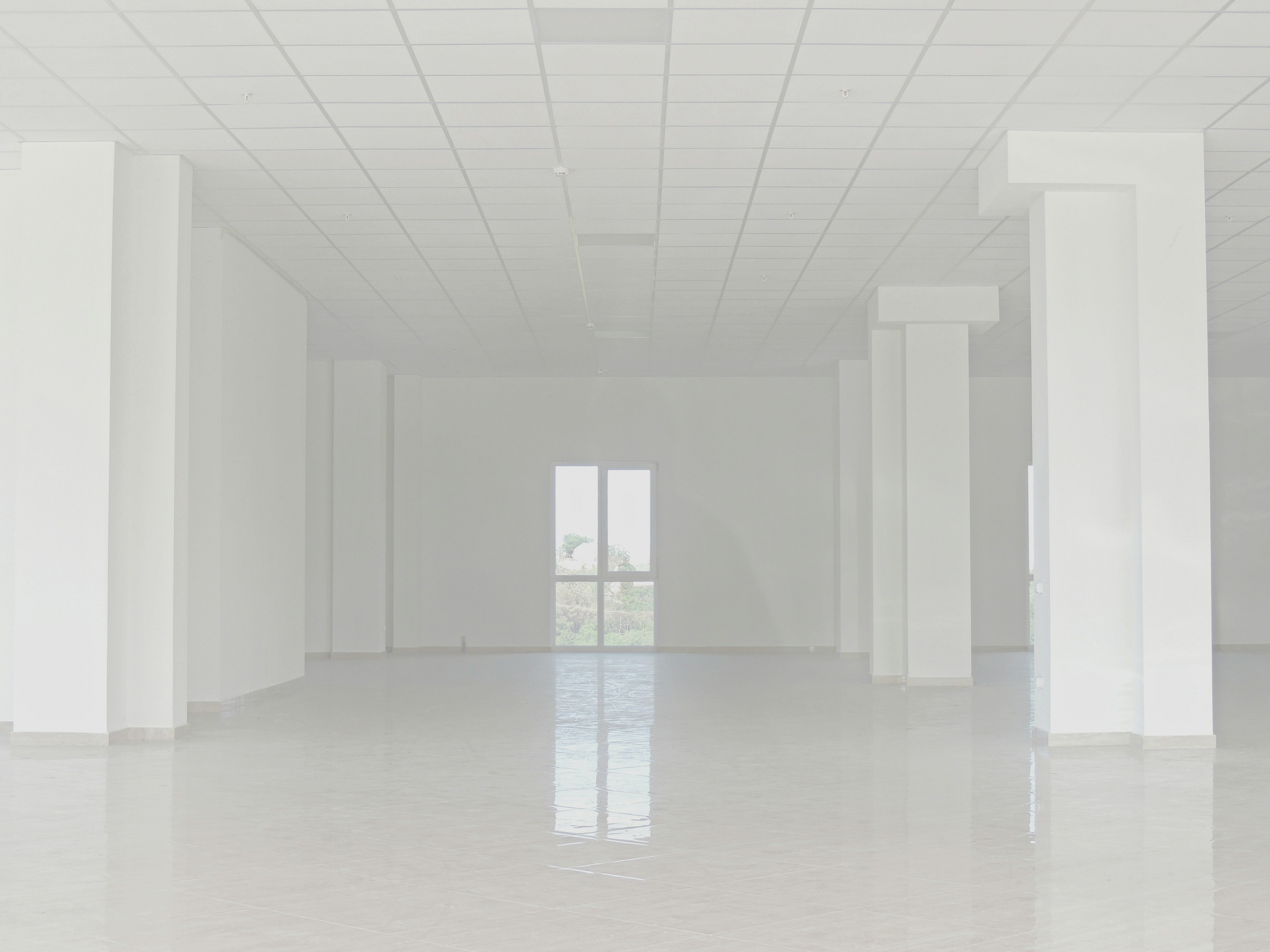 Empty white commercial space with tiled floor and columns